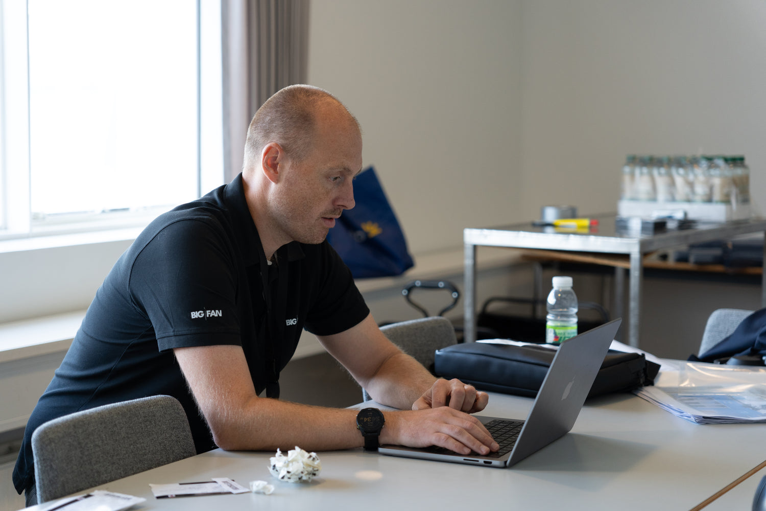 mand der sidder ved et bord og arbejder på sin computer